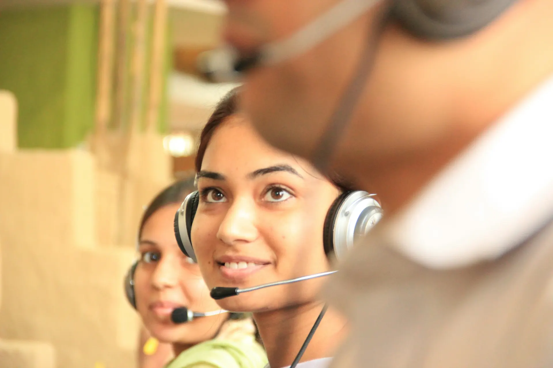 Smiling call center agents wearing headsets sit side by side.