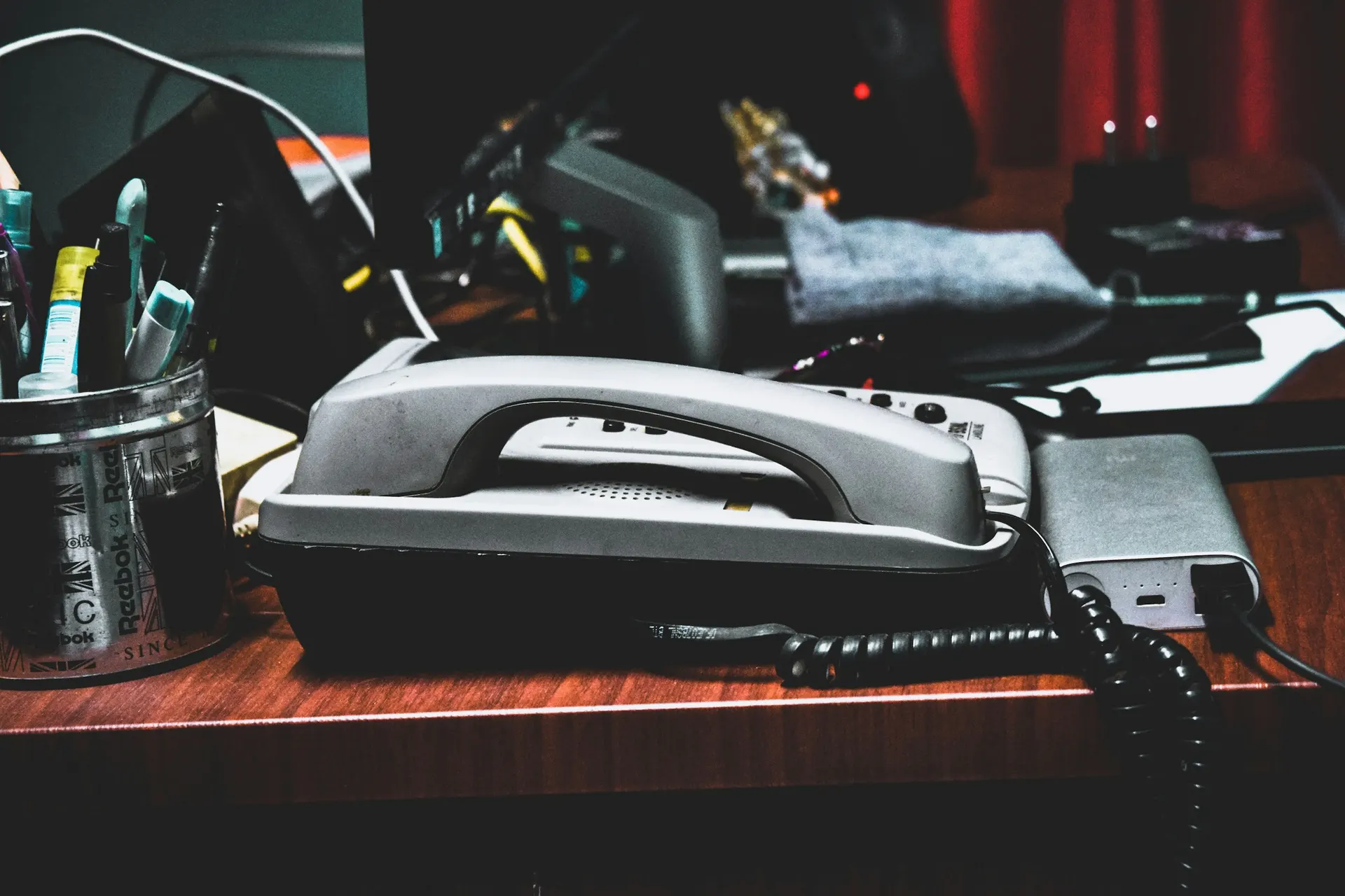 A gray corded desk telephone on a busy office desk.
