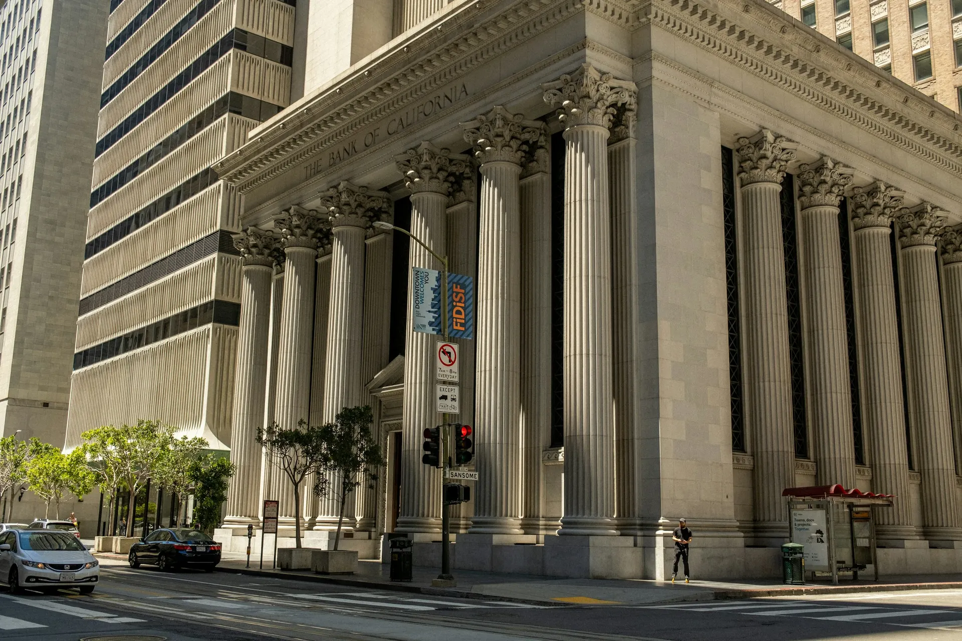 A columned civic building on a city street corner.
