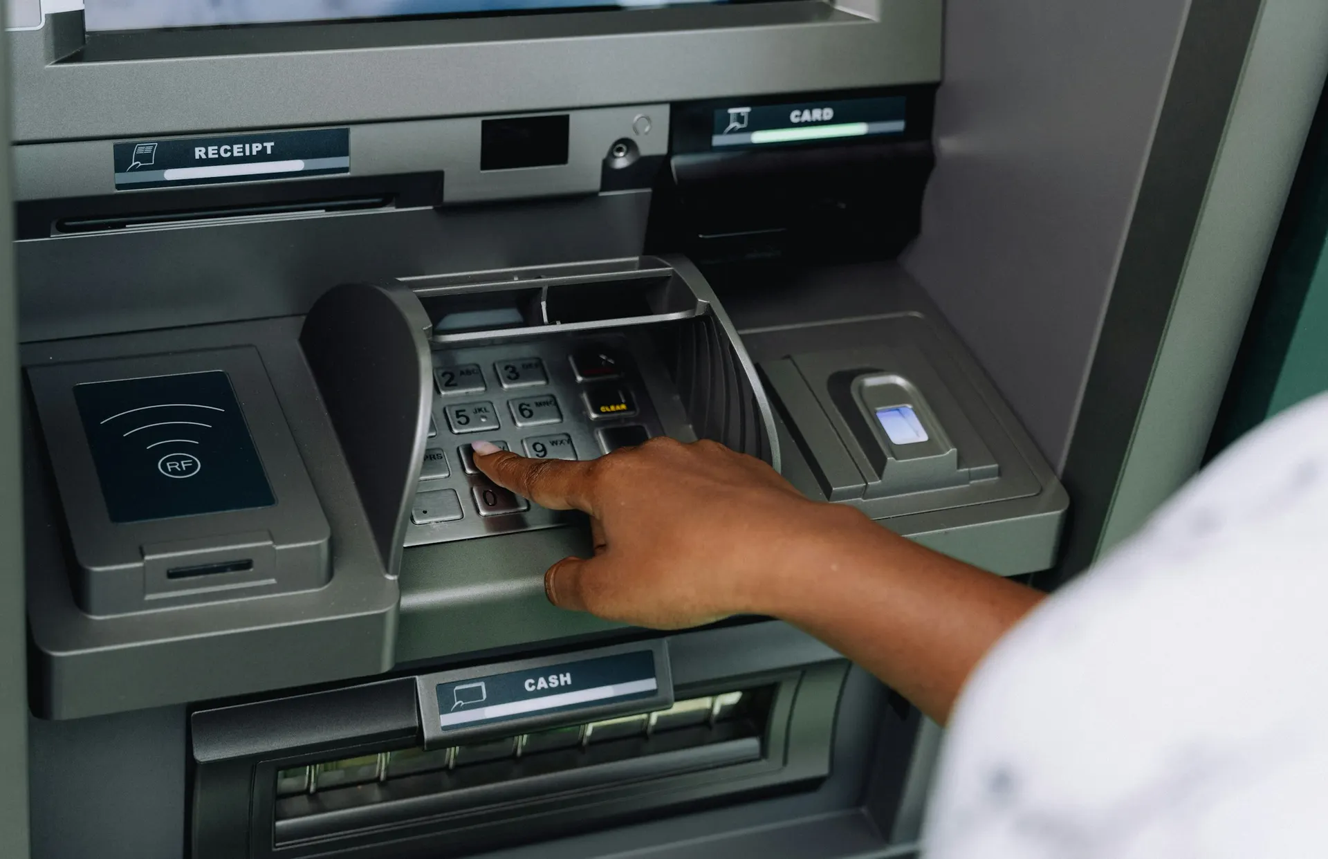 A customer enters a PIN on an ATM keypad.